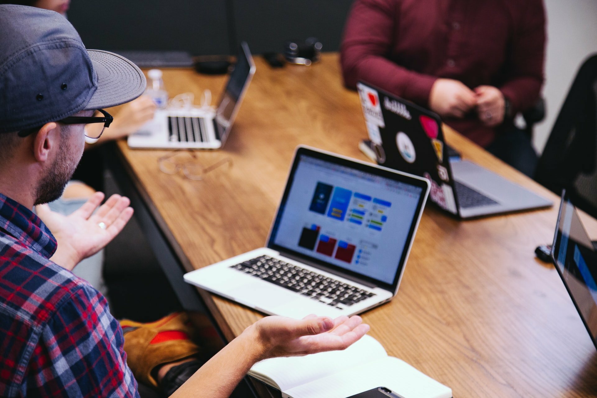 a group of people sitting at a table with laptops